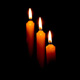 three candles against a dark background