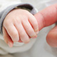 hand of baby holding on to finger of parent