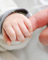 hand of baby holding on to finger of parent