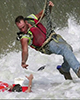 Rescuer being lowered from helicopter reaching down to grab person from turbulent water