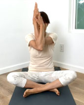 左に体をひねったヨガポーズをしている黒い服を着た女性