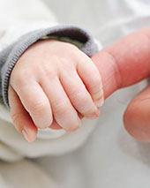 Mão de bebê segurando dedo de pai/mãe